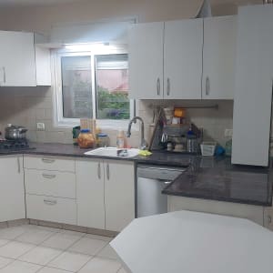 מטבח עם ארונות לבנים ומשטחי עבודה כהים