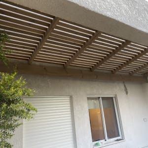 פרגולה מעץ מעל חלון עם תריס סגור