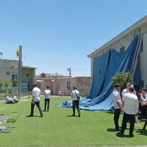 אנשים ליד מבנה עם כיסוי כחול וסולמות