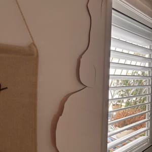 קיר עם סדקים ליד חלון עם תריסים