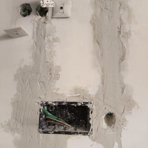 עבודות חשמל בקיר עם שקעים וחוטים חשופים