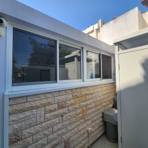 חלונות אלומיניום במסגרת לבנה על קיר חיצוני