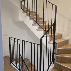 מעקה מתכת שחור על גרם מדרגות עץ