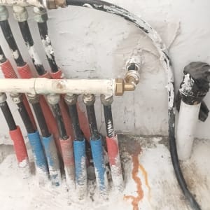 צינורות מים עם חיבורים על קיר לבן