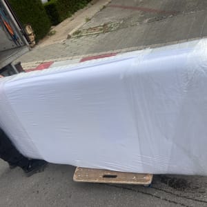 מזרן עטוף בניילון על עגלה ליד משאית