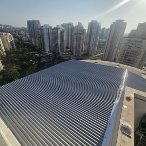 גג מתכת על בניין גבוה עם נוף עירוני ברקע