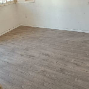 רצפת פרקט עץ בהירה בחדר ריק עם קירות לבנים