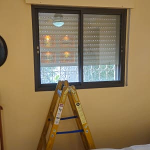 סולם ליד חלון עם תריסים בחדר