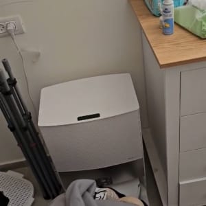 בגדים מקופלים על הרצפה ליד ארון ומכשיר חשמלי