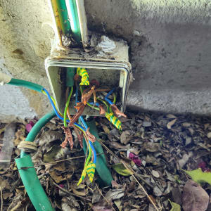 חוטי חשמל חשופים בקופסת חיבורים על קיר