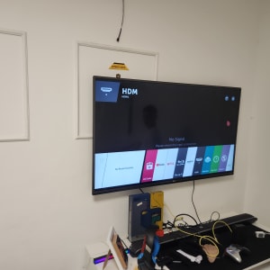 כלים על שולחן ליד טלוויזיה תלויה על הקיר