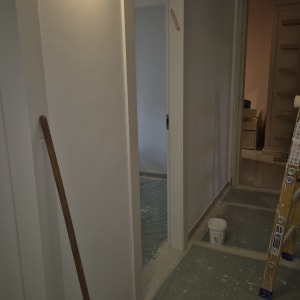 מסדרון עם סולם, דלי צבע ומברשת על הרצפה