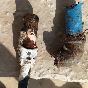 צינורות חלודים עם נזק, מונחים על משטח בטון