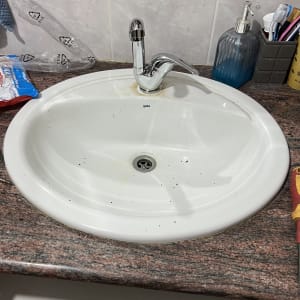 ברז כרום מבריק מותקן על כיור רחצה לבן במשטח שיש