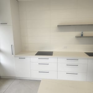 מטבח נקי עם משטחי עבודה לבנים ומדפים