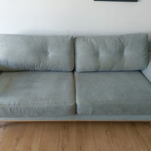 ספה אפורה עם כתמים על רצפת עץ