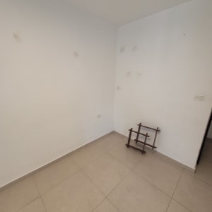 קיר לבן עם סימני לכלוך ומתקן עץ על הרצפה