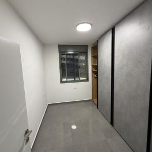 חדר ריק עם קירות לבנים ורצפת אריחים אפורה