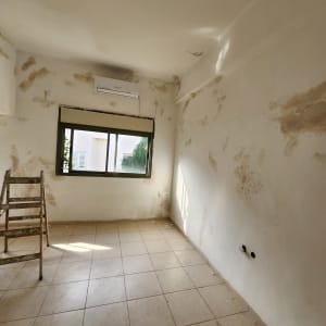 חדר עם קירות מתקלפים וסולם עץ