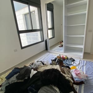 בגדים מפוזרים על הרצפה ליד ארון פתוח