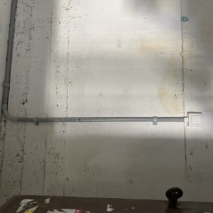 צינור חשמל אפור על קיר לבן עם תיבת חיבורים