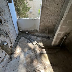 קירות בטון חשופים עם צינורות ותעלות ברצפה