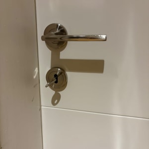 ידית ניקל וצילינדר עם מפתח מותקנים על דלת פנים לבנה