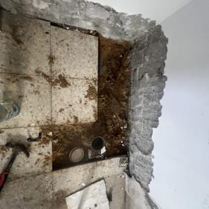 תמונה של עבודת תיקון קיר ורצפה עם כלים וחומרים