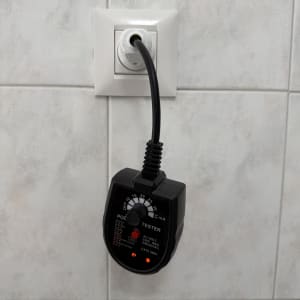 בודק חשמל מחובר לשקע בקיר