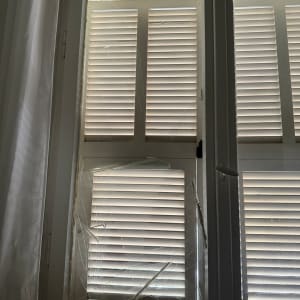 חלון עם זכוכית שבורה ותריסים סגורים