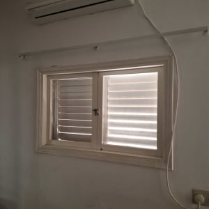 חלון עם תריסים ומזגן על הקיר