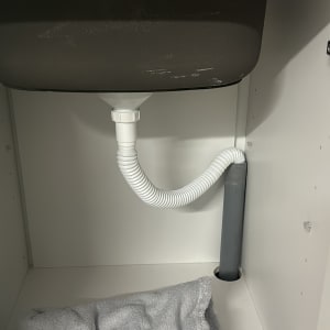 כיור עם ברז וצינור ניקוז מתחת לארון