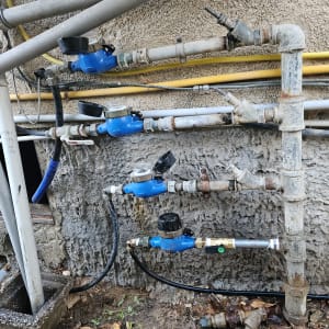 צנרת מים עם מדי מים כחולים על קיר חיצוני