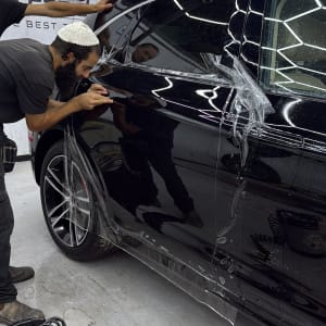 אדם מבצע עבודת דיטיילינג על רכב שחור עם כלים מקצועיים