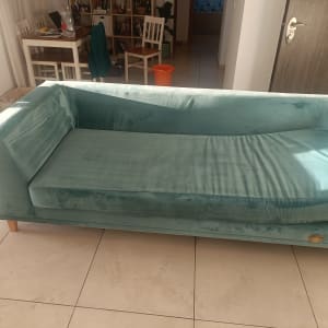 ספה ירוקה על רצפת אריחים בחדר מואר