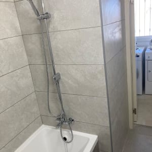 אמבטיה חדשה עם אריחים אפורים ומקלחת מותקנת