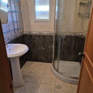 חדר אמבטיה עם מקלחון, כיור ומדף מתכת