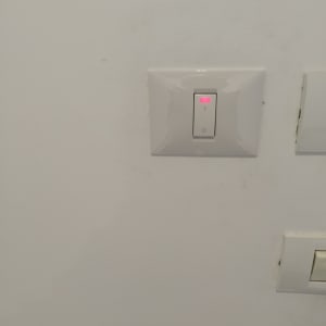 מתג חשמל עם נורית חיווי אדומה על קיר לבן