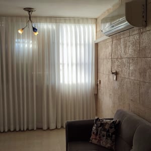 וילון לבן ארוך תלוי על חלון גדול