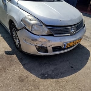 פגוש קדמי של רכב ניסאן כסוף עם נזק ושריטות לפני תיקון פחחות
