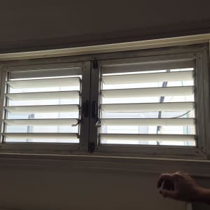 תריסים מותקנים על חלון עם יד אדם נראית בצד