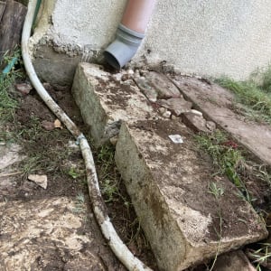 צינור ניקוז ליד קיר חיצוני עם בלוקים ואדמה