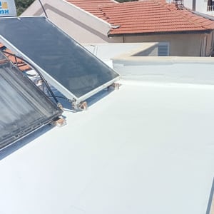גג שטוח עם קולטי שמש ואיטום לבן