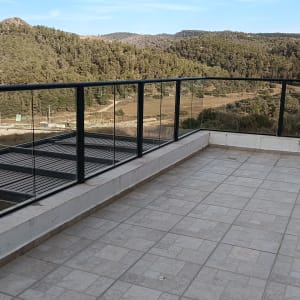 מעקה זכוכית נקי ושקוף במרפסת מרוצפת המשקיפה לנוף פתוח