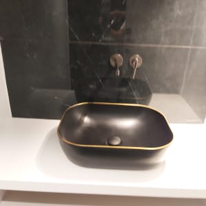 כיור שחור עם ברזים על קיר שיש כהה