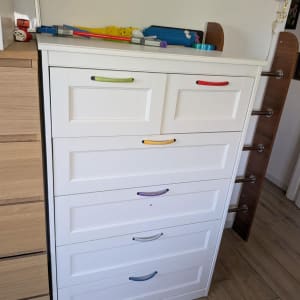 שידה לבנה עם ידיות צבעוניות בחדר
