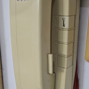 אינטרקום ישן עם מדבקה ירוקה על הקיר