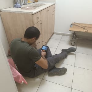 אדם יושב על הרצפה עם מכשיר אלקטרוני ביד