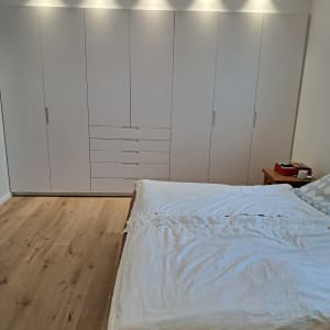 ארון בגדים לבן עם דלתות ומגירות בחדר שינה