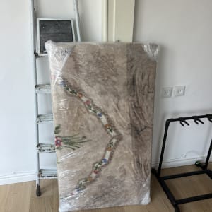 סולם ומזרן עטוף בניילון ליד קיר לבן